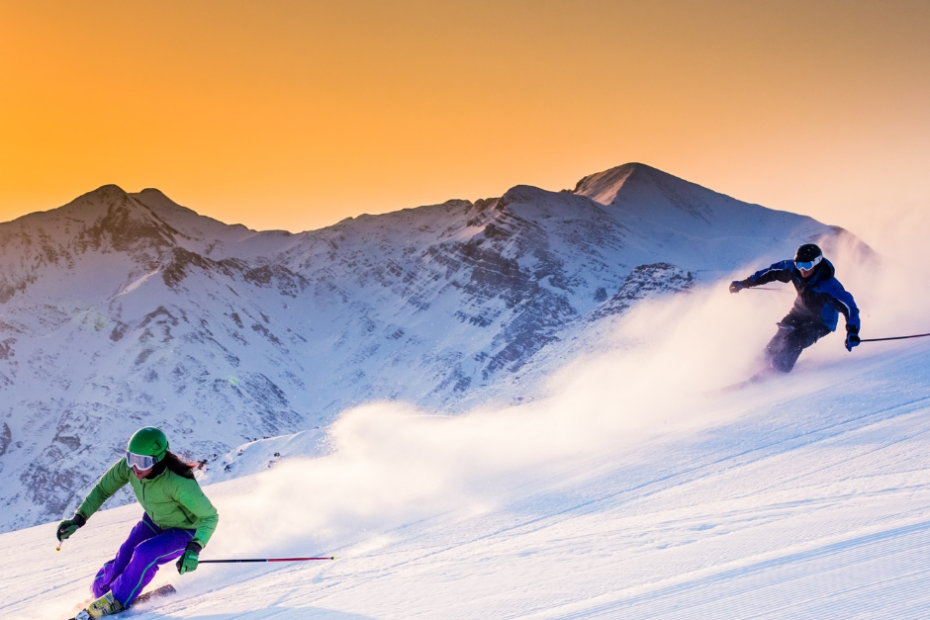 Emoción compartida en la nieve: Dos intrépidos aventureros deslizándose por las majestuosas pistas de esquí